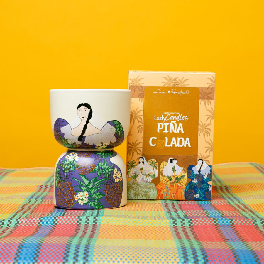 Decorative candle including a colorful vase and a box with a character design on a checkered tablecloth against a yellow background.